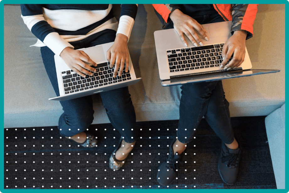 An overhead shot of two people sitting side by side with laptops on their laps