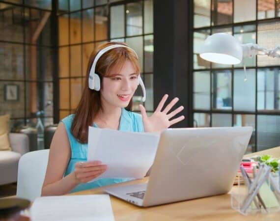 Woman waving at someone on her computer during an interview.