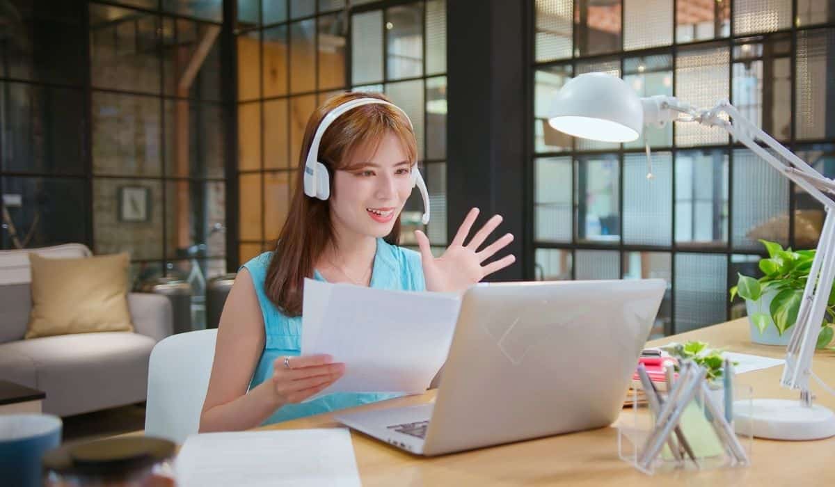 Woman waving at someone on her computer during an interview.