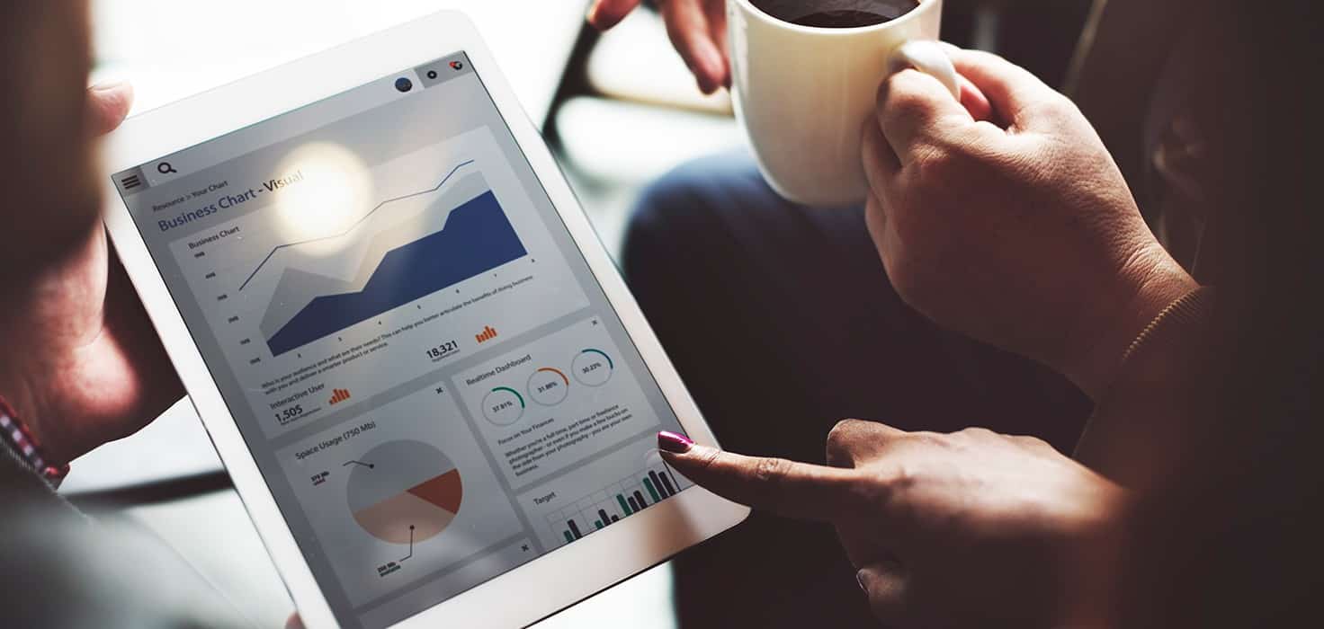 A person holding a tablet and a mug of coffee. The tablet shows charts and data representing a win/loss analysis.