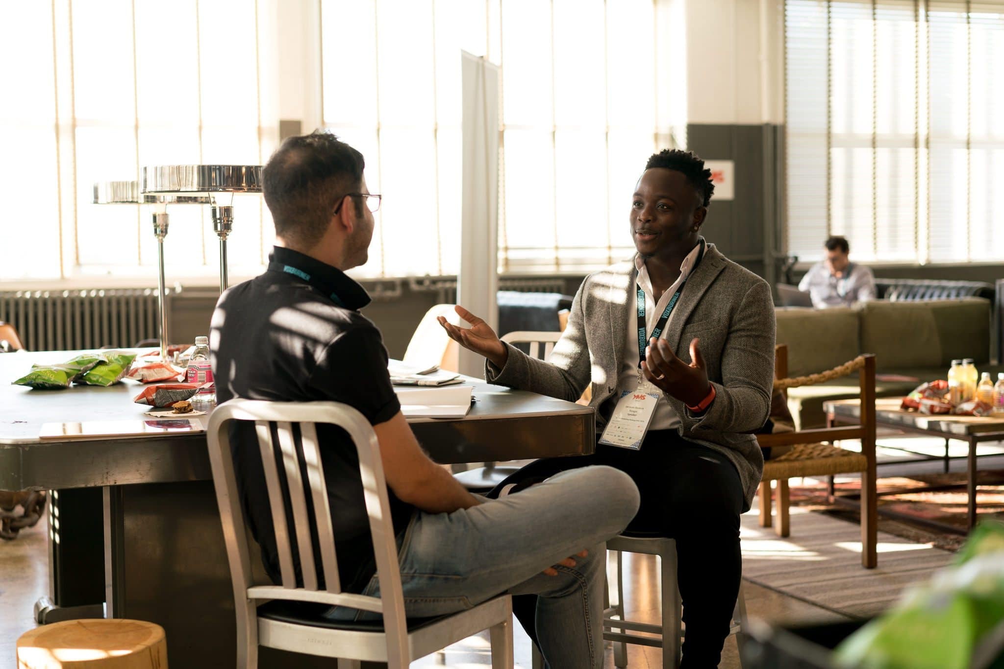 Two men sitting at a desk during a customer visit, engaged in conversation.