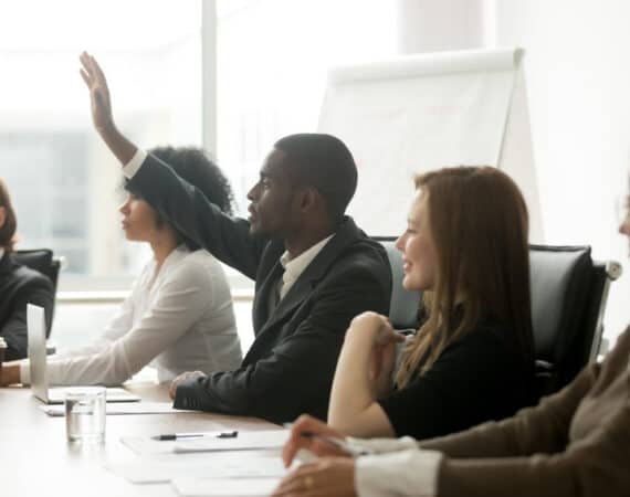 executive raising hand at team meeting