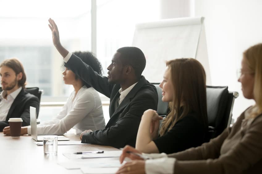 executive raising hand at team meeting