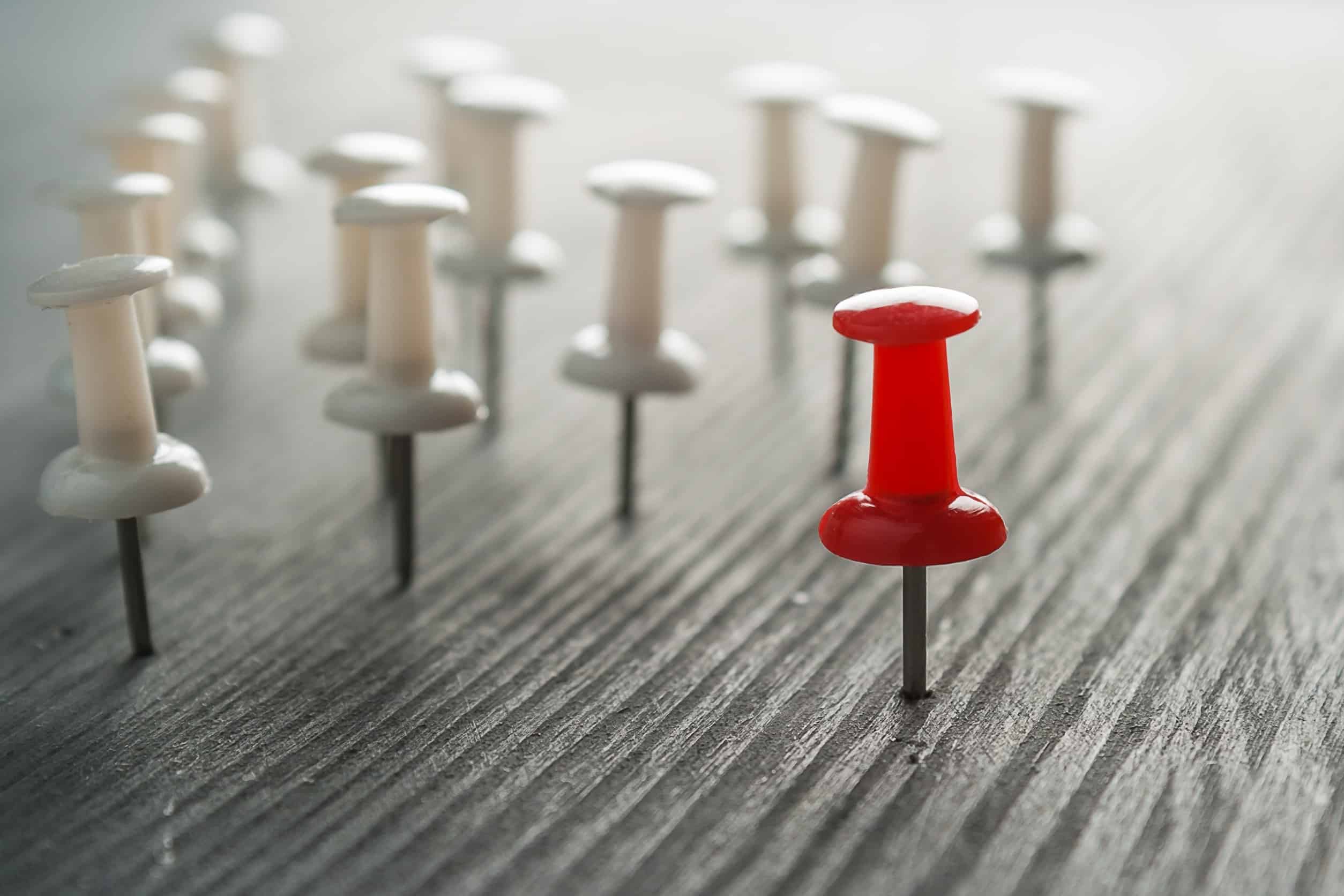 A red pushpin standing out against many white pushpins, representing distinctive competencies.
