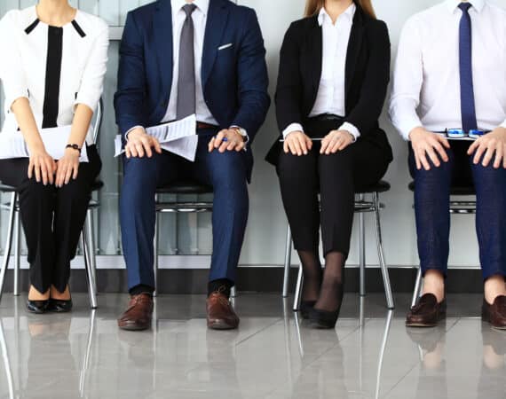 Four people in business attire waiting for a product manager job interview.