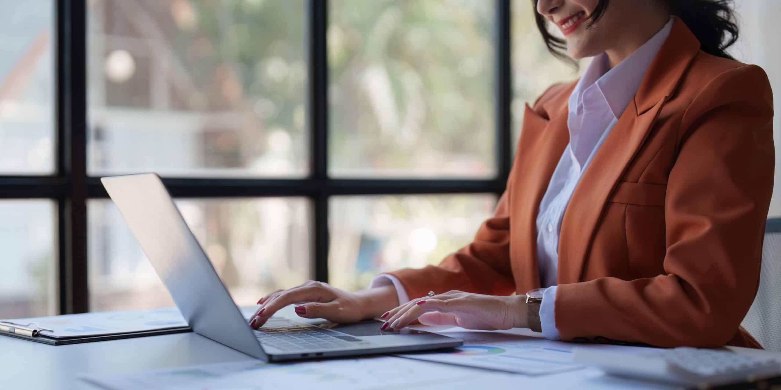 A female product manager sitting at a desk, searching for product management certifications on her laptop.