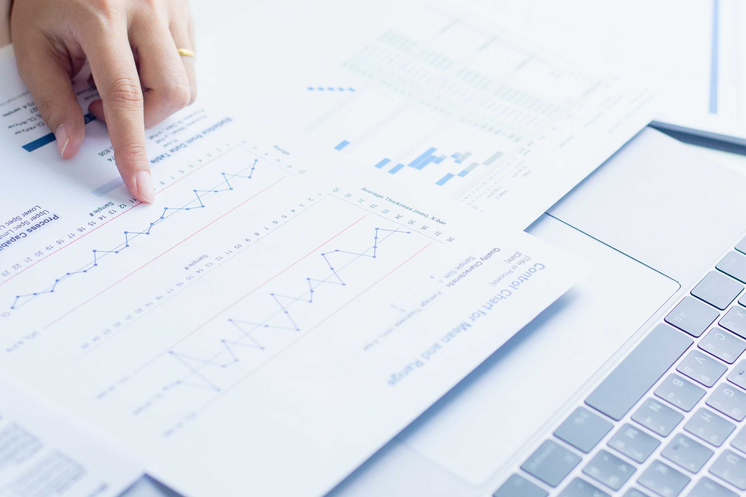 A data scientist creating visualizations to communicate information, pointing to charts on a printed piece of paper.