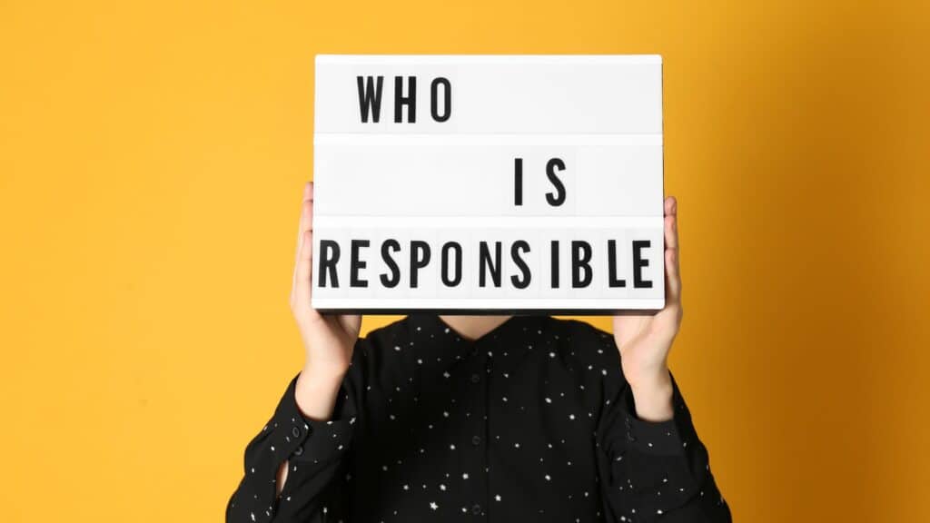 A person holding up a sign that say who is responsible